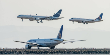 a-united-airlines-plane-and-delta-airlines-with-skyteam-livery-plane-come-into-land-while-a-united-airlines-plane-waits-at-the-end-of-the-runway-2018