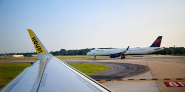 a-spirit-jet-waits-behind-a-delta-plane-to-take-off-at-hartsfield-jackson-atlanta-international-airport